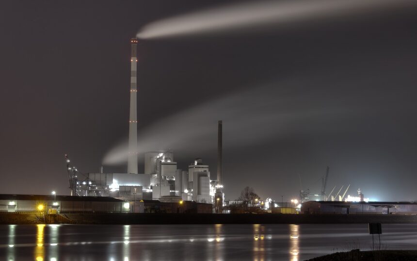 una ciminiera con il suo pennacchio di fumi in una foto notturna